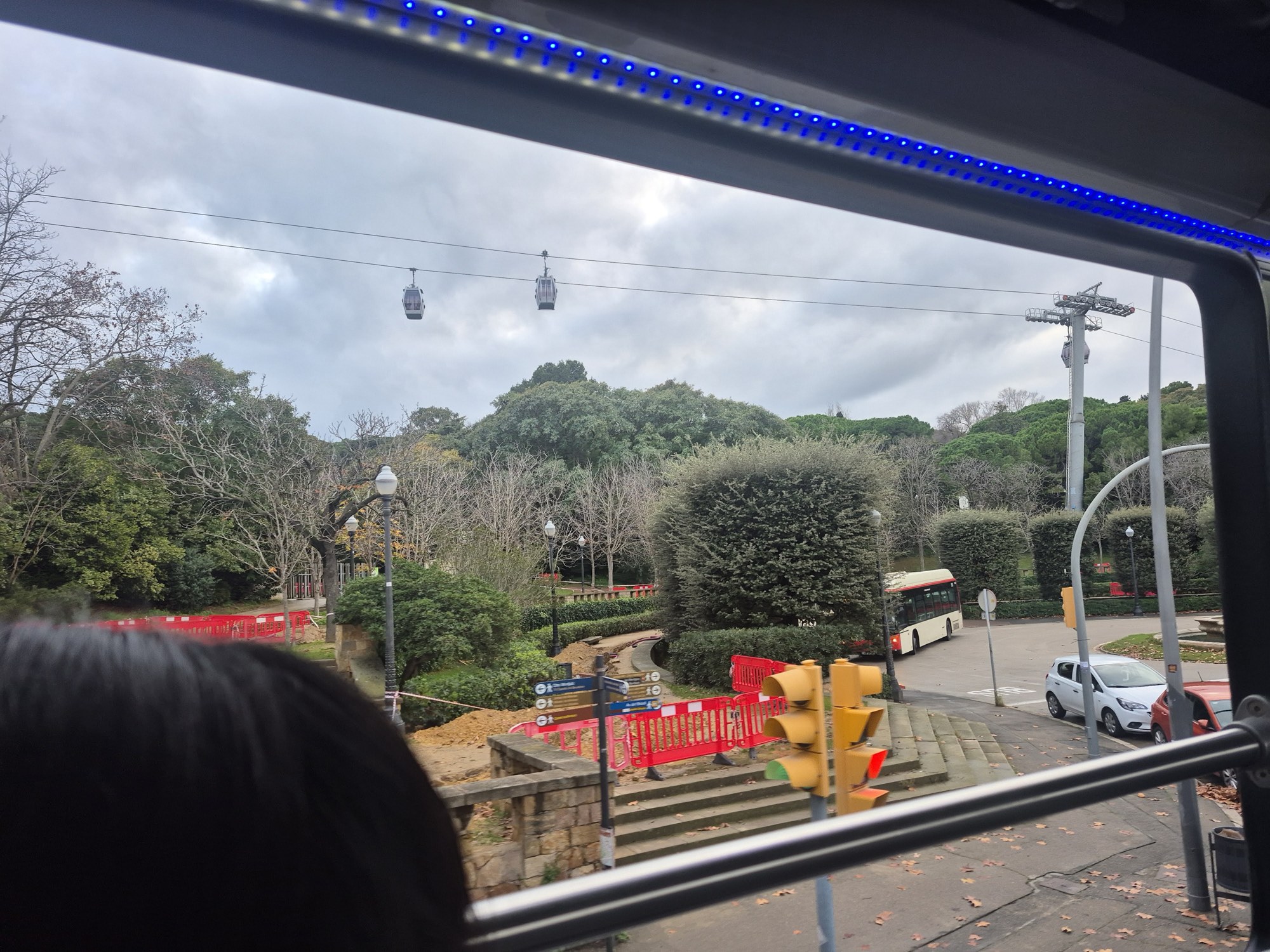 Looking out of a Montjuïc cable-car cabin at the cabins ahead climbing over the wooded hillside toward the castle
